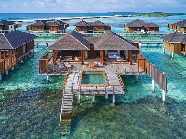 Luxury overwater bungalows with thatched roofs at Villa Nautica Paradise Island Resort in the Maldives, featuring turquoise l